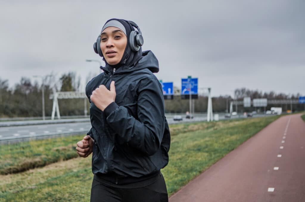 Young woman training running in the rain wearing a hijab